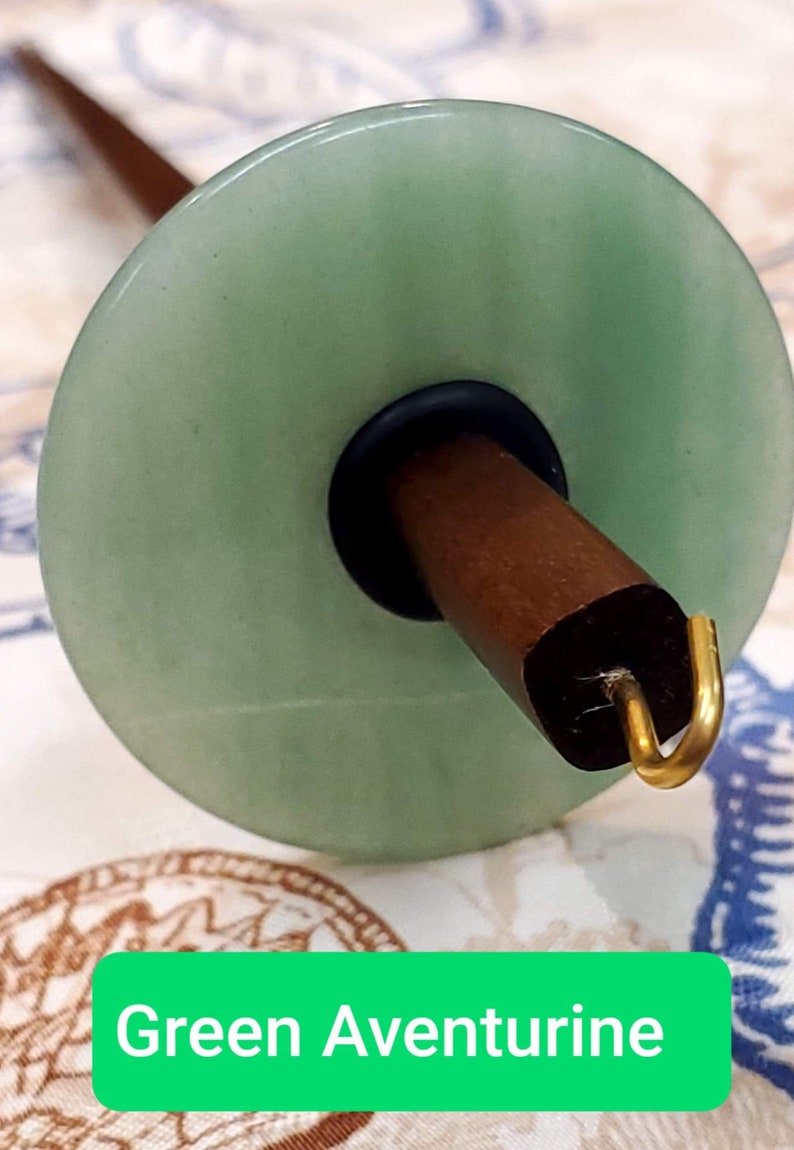 May include: Green aventurine spinning wheel whorl with a brown wooden spindle and a gold hook.