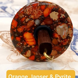May include: A spinning wheel whorl with a brown wooden shaft and a round orange, brown, and white jasper and pyrite whorl. The whorl has a gold metal hook.