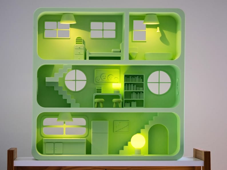 Puede incluir: Una casa de mu&ntilde;ecas verde con varias habitaciones, incluyendo un dormitorio, un ba&ntilde;o y una cocina. La casa tiene escaleras, ventanas y muebles. El interior est&aacute; iluminado con luces amarillas, creando un brillo c&aacute;lido. El dise&ntilde;o es minimalista y moderno.