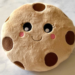 May include: A plush brown cookie with a smiling face, chocolate chips, and pink cheeks.
