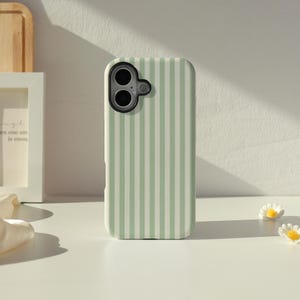 May include: A mint green and white striped phone case. The case features a vertical stripe design and a camera aperture. The phone case is on a white surface with small daisy decorations.