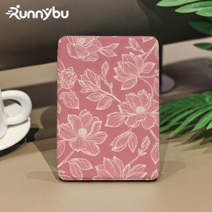 Pode incluir: Uma capa retangular para leitor de e-books na cor rosa seco com um padrão de linhas brancas de flores de magnólia e folhas. O nome da marca Runnybu está impresso em texto branco no canto superior esquerdo da imagem.
