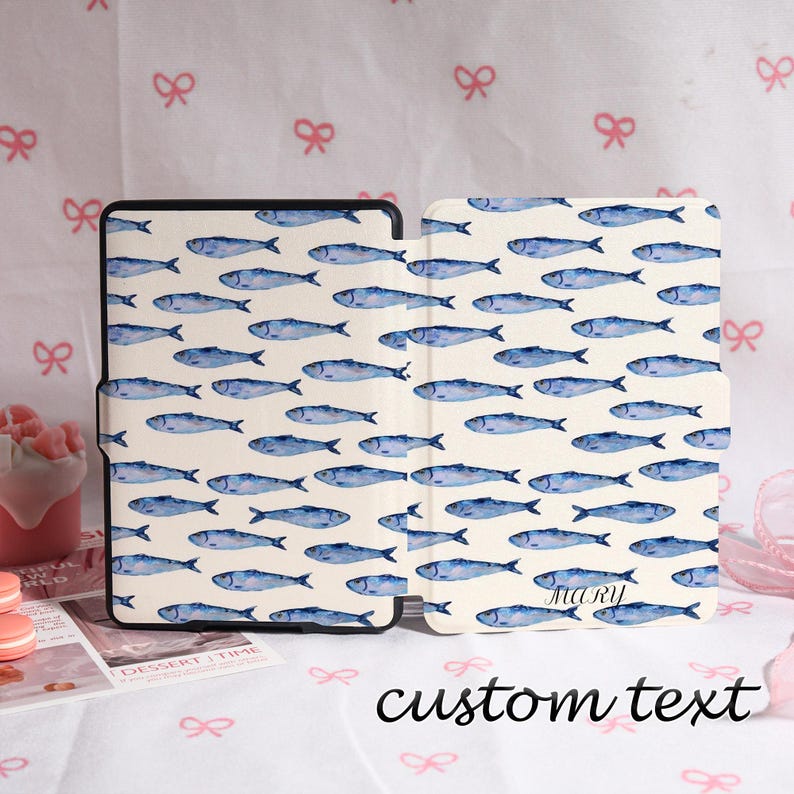 May include: A tablet case with a repeating pattern of blue watercolor fish on a cream background. The case is open, revealing the interior and exterior design. The text "custom text" is written in black script at the bottom.