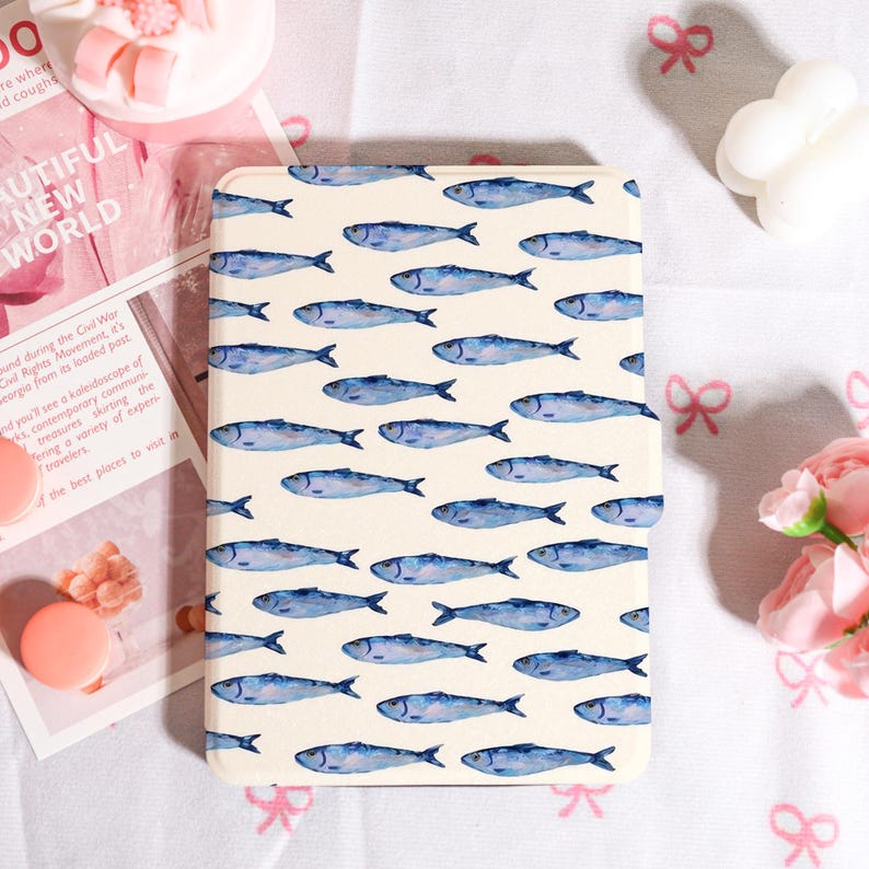 May include: A cream-colored tablet case featuring a repeating pattern of blue watercolor fish. The fish are oriented horizontally across the surface. The case has rounded corners and a smooth finish.