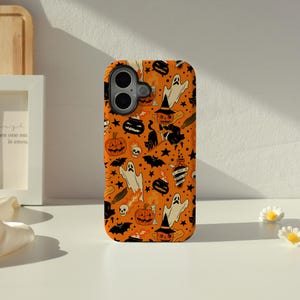 May include: A rectangular phone case with an orange background featuring a repeating Halloween pattern of black cats, white ghosts, orange jack-o'-lanterns, black bats, skulls, cauldrons, and a potion bottle with the text I PUT A SPELL ON YOU.
