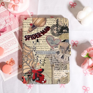 Peut inclure: Un carnet décoratif avec un design de collage. La couverture présente les mots "Spider-Man" et "Peter Parker", une toile d'araignée, une horloge et des éléments de style vintage. La palette de couleurs est principalement rouge, noir et beige.