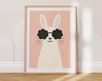 Könnte beinhalten: Gerahmter Kunstdruck mit einem weißen Hasen, der eine schwarze Sonnenbrille in Blütenform vor einem zartrosa Hintergrund trägt. Der Hase hat lange Ohren und Schnurrhaare. Das Kunstwerk ist in einem hellen Holzrahmen, für Kinderzimmer.