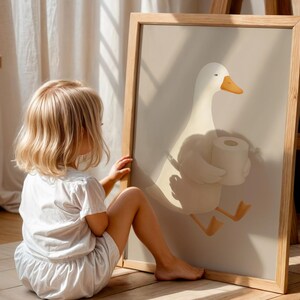 Funny goose toilet paper art for kids, humorous potty training bathroom print, child interacting with bathroom wall art, playful goose carrying toilet paper illustration, toddler bathroom decor ideas, Montessori style bathroom humor art, oversized funny bathroom poster for children, natural wood frame goose print, lighthearted potty training encouragement, gender neutral kids bathroom wall decor, rustic farmhouse children's bathroom art, educational toilet training wall print.