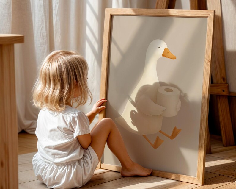 Funny goose toilet paper art for kids, humorous potty training bathroom print, child interacting with bathroom wall art, playful goose carrying toilet paper illustration, toddler bathroom decor ideas, Montessori style bathroom humor art, oversized funny bathroom poster for children, natural wood frame goose print, lighthearted potty training encouragement, gender neutral kids bathroom wall decor, rustic farmhouse children's bathroom art, educational toilet training wall print.
