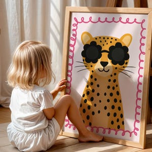 Cute cheetah wall art with flower sunglasses, toddler girl enjoying adorable leopard poster with pink border, perfect kids room decor, child-friendly animal art, interactive nursery wall print, engaging children's artwork, playful kids bedroom decoration, spotted cat illustration, fun animal poster kids, colorful nursery art, whimsical children's decor, wooden frame kids art, toddler room styling, child development wall art, educational animal print, happy kids room design, bright nursery poster