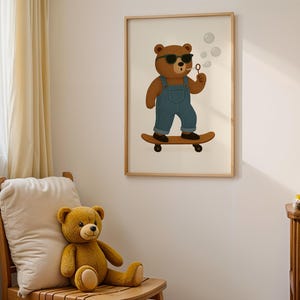 Skateboarding bear nursery wall art printable in cozy reading nook with wooden chair and teddy bears – cute bear with sunglasses, overalls, and bubbles on skateboard – digital download animal poster for kids room, baby nursery, or playroom – gender-neutral bear wall art in warm neutral tones – modern children’s decor for boys or girls – instant download framed artwork – woodland nursery interior design – bear illustration for boho toddler bedroom styling.