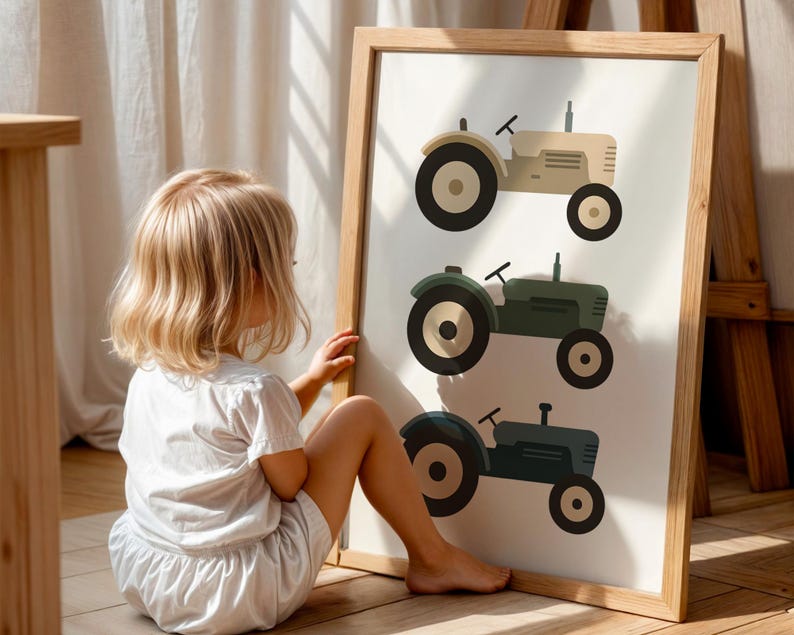 Little blonde girl admiring vintage tractor illustration art print in sunlit playroom, farm themed nursery wall decor with three tractors in neutral earth tones, beige green blue tractor poster for toddler boys room, rustic farmhouse kids bedroom artwork, vehicle transportation print children love, modern minimalist farm nursery aesthetic, large statement wall art in natural oak frame, country style children's room decoration, tractor loving toddler gift idea, warm golden light playroom styling.