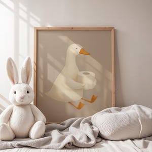 White goose toilet paper wall art, funny bathroom print for nursery, humorous potty training decor, playful goose carrying toilet paper poster, gender neutral children's bathroom art, Scandinavian style bathroom humor print, natural light nursery bathroom decor, wooden frame funny goose illustration, minimalist kids bathroom wall art, whimsical farmhouse bathroom poster, soft neutral bathroom decor for kids, lighthearted potty training encouragement art, modern nursery bathroom humor.