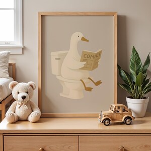 Funny duck bathroom art print, humorous animal wall decor poster, duck reading newspaper on toilet illustration, quirky bathroom wall art, cute duck comics print, minimalist bathroom humor decor, neutral beige bathroom poster, Scandinavian style wall art, modern farmhouse bathroom print, whimsical animal illustration, restroom wall hanging, powder room decor art, housewarming gift idea, unique bathroom sign, hygge home decor poster, natural wood frame art, playful duck artwork, guest bathroom.