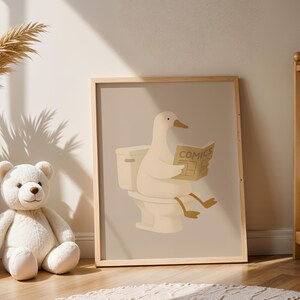 Funny duck bathroom art print for kids nursery, whimsical animal reading on toilet poster, nursery bathroom decor, children's room wall art, cute duck illustration for baby room, playful bathroom humor kids art, neutral beige nursery print, Scandinavian children's decor, minimalist kids bathroom poster, duck reading comics artwork, gender neutral nursery art, modern farmhouse kids room, soft neutral tones children's print, adorable animal bathroom sign, toddler bathroom wall decor.