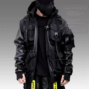 May include: A black leather jacket with a black hooded sweatshirt underneath. The jacket has multiple pockets and straps, and the sweatshirt has a zipper closure. The model is wearing a black face mask and black pants with yellow straps.