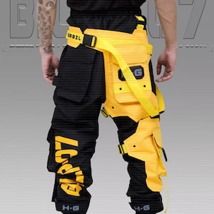 Puede incluir: Pantalones cargo negros y amarillos con m&uacute;ltiples bolsillos y correas. Los pantalones presentan detalles amarillos en las piernas y la cintura, con el texto "G7" impreso en amarillo en la pierna izquierda. El cintur&oacute;n de la cintura tiene el texto "GRAIL".
