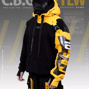 Puede incluir: Una sudadera con capucha negra y amarilla con cremallera y un gran gráfico en la manga. El gráfico dice "HOLYGRAIL" y "C.B.G. YLW".