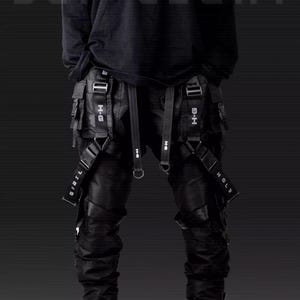 May include: Black cargo pants with multiple straps and buckles. The straps have the text "HOLY" and "BIBII" printed on them. The pants have a black belt with the text "H-H" printed on the buckles.