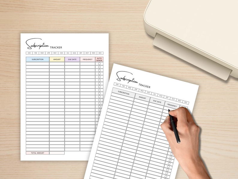 May include: Two white subscription tracker sheets with a light wood background. The sheets have a header that says "Subscription Tracker" and include columns for subscription, amount, due date, frequency, and auto-renew. A hand is holding a pen, writing on one of the sheets.