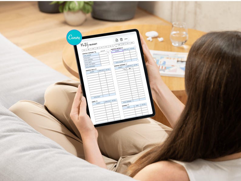 May include: A tablet displaying a "Monthly Budget" template is held by a person. The template includes sections for income and expenses. The tablet is black with a white screen, and the text is in black. The Canva logo is visible in the upper left corner.