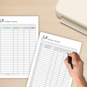 May include: Two white bill payment tracker sheets with a light beige background. The sheets have a header that says "Bill Payment Tracker". One sheet is being written on with a black pen. The sheets are next to a white printer.