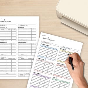 May include: Two white sheets of paper with a travel budget template printed on them. The template includes sections for expenses, budget, and actual costs. A hand is holding a pen, filling out the budget.