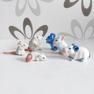 May include: A set of six ceramic mouse figurines. The mice are in various poses, including sitting, standing, and lying down. They are painted in white, blue, and pink.