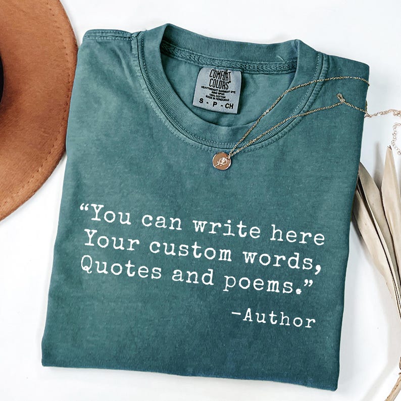 May include: A teal Comfort Colors t-shirt with the text "You can write here Your custom words, Quotes and poems." and "-Author" in white. A gold necklace with a pendant is on the shirt.