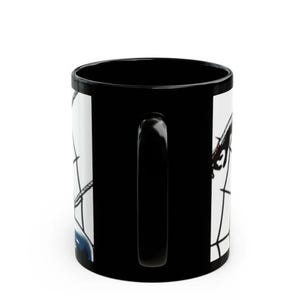 May include: Black coffee mug with a white graphic design. The mug features a black handle and a glossy finish. The graphic design appears to be a stylized illustration with black and red elements.