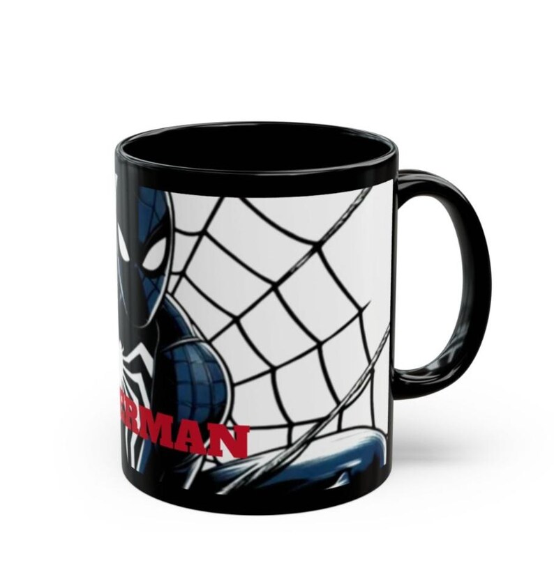 May include: Black ceramic mug featuring a Spiderman design. The mug has a black handle and interior. The Spiderman graphic includes a black and blue Spiderman with a white spiderweb background and the word "Spiderman" in red.