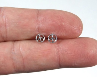 May include: A pair of silver peace sign stud earrings. The earrings are small and delicate, and they are perfect for everyday wear.