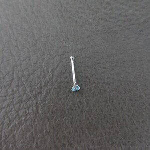May include: A silver guitar pick with a blue heart design.