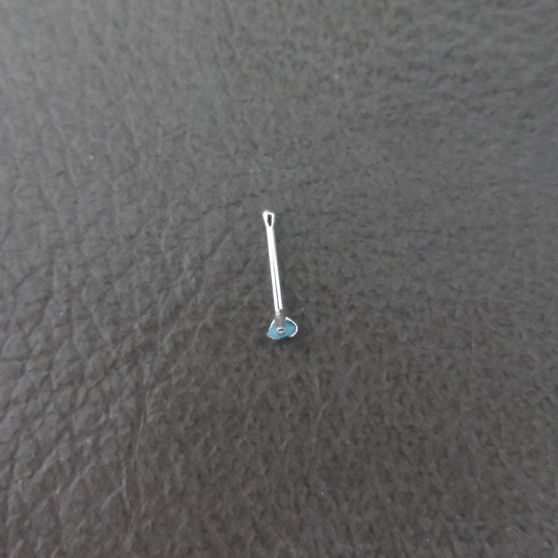 May include: A silver guitar pick with a blue heart design.