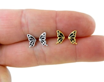 Könnte beinhalten: Ein Paar Schmetterlings-Ohrstecker, ein Paar ist silber mit schwarzen Schmetterlingsflügeln und das andere Paar ist gold mit schwarzen Schmetterlingsflügeln.