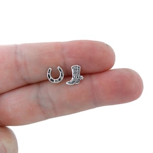 May include: A pair of silver stud earrings featuring a horseshoe and a cowboy boot design.