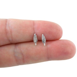 May include: A pair of small, silver-colored stud earrings. Each earring is shaped like a miniature corn cob, with detailed texture. The earrings are displayed against a neutral background.