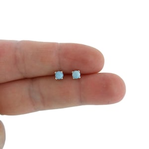 May include: A pair of silver stud earrings with light blue round gemstones.