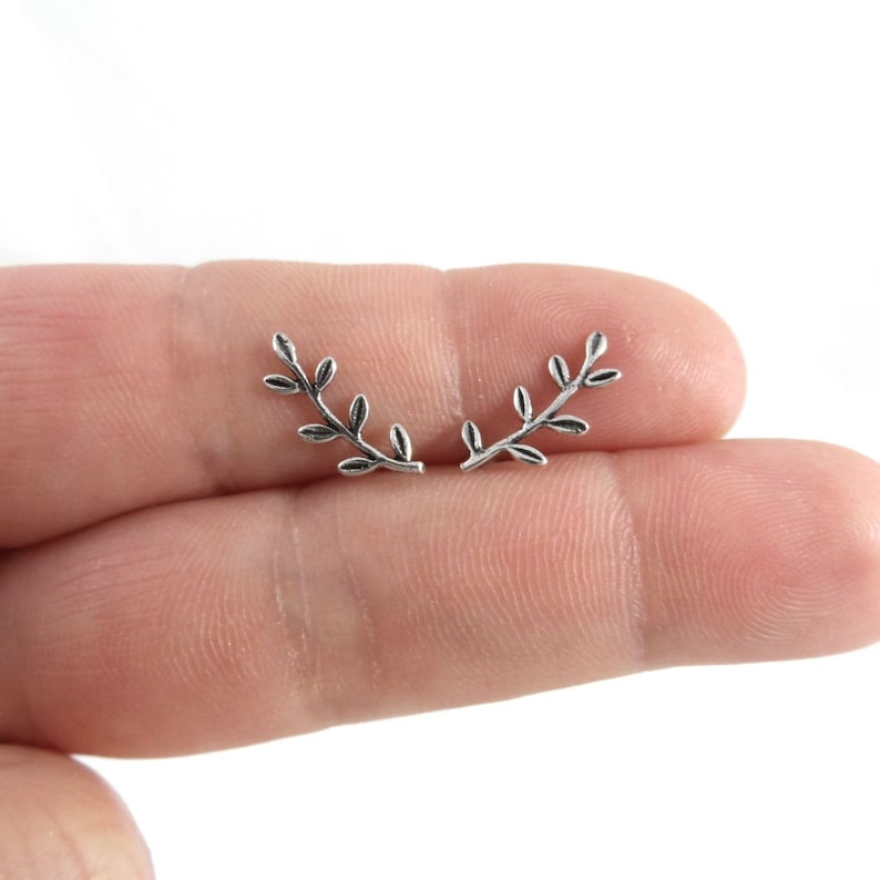Puede incluir: Un par de pendientes de plata con forma de ramas delicadas con peque&ntilde;as hojas.