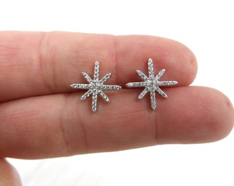 May include: A pair of silver star-shaped earrings with clear cubic zirconia stones.
