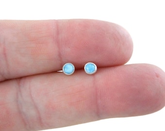 May include: A pair of silver stud earrings with small, round, light blue gemstones.
