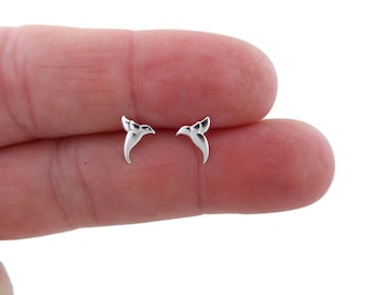 May include: A pair of silver hummingbird stud earrings. The earrings are small and delicate, and they feature a detailed hummingbird design.