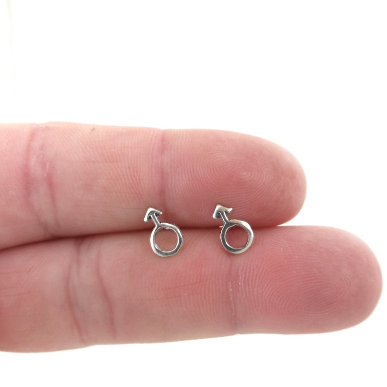 May include: A pair of silver stud earrings with a male symbol design.