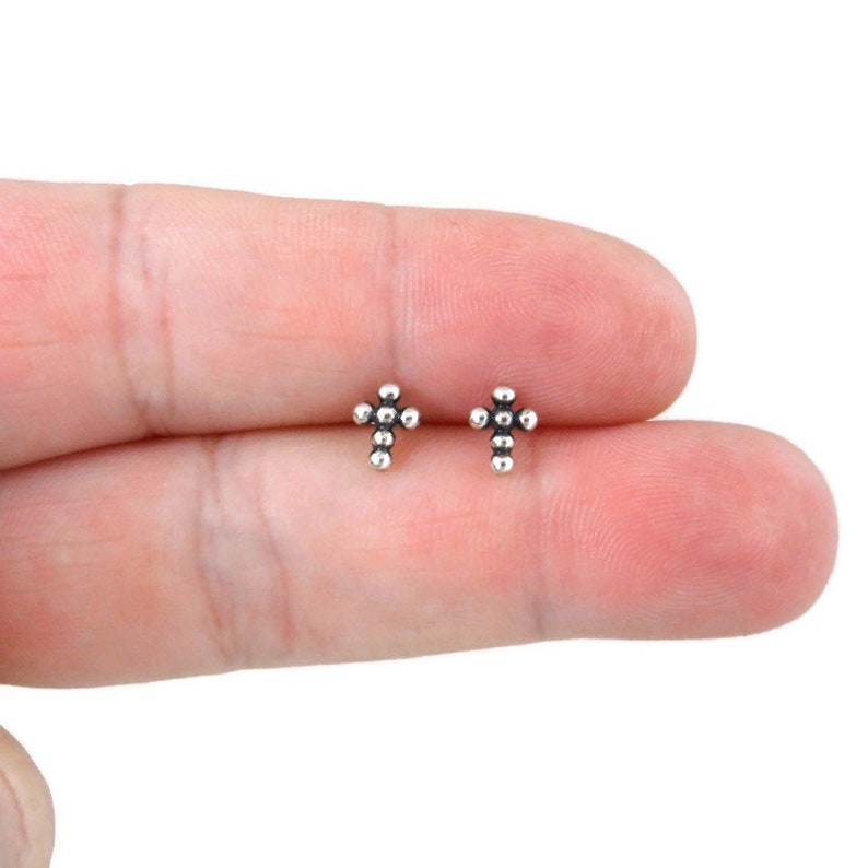 May include: A pair of silver cross stud earrings. Each earring features a small cross design made of tiny silver beads.