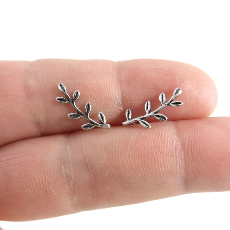 Puede incluir: Un par de pendientes de plata con forma de ramas delicadas con peque&ntilde;as hojas.