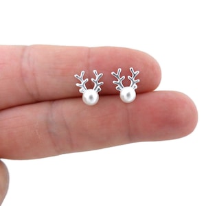 Puede incluir: Un par de pendientes de botón de reno de plata con detalles de perlas blancas.