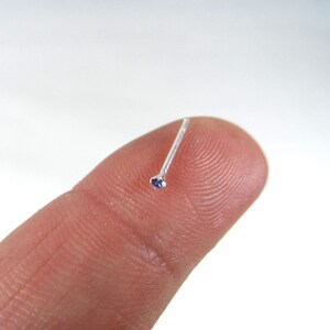 May include: A silver nose ring with a small blue gemstone.