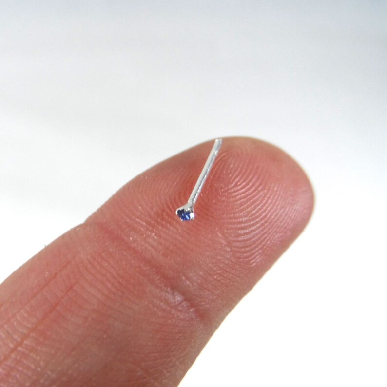 May include: A silver nose ring with a small blue gemstone.