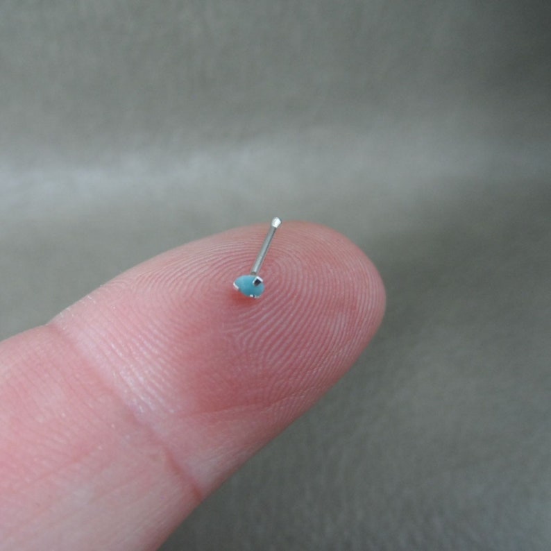 May include: A silver nose ring with a small, light blue gemstone.