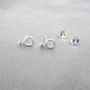 May include: A pair of silver stud earrings featuring a male symbol design. The earrings are marked with "925" on the back.
